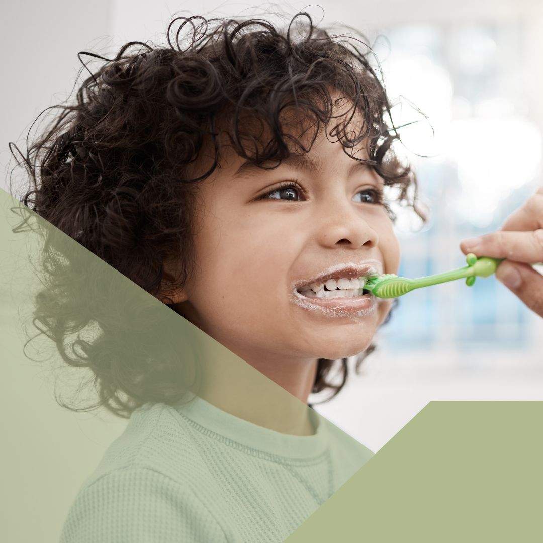 parent helping little boy brush teeth