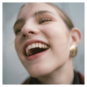 woman wearing gold earrings smiles close up 