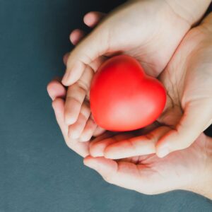 two hands holding a foam red heart